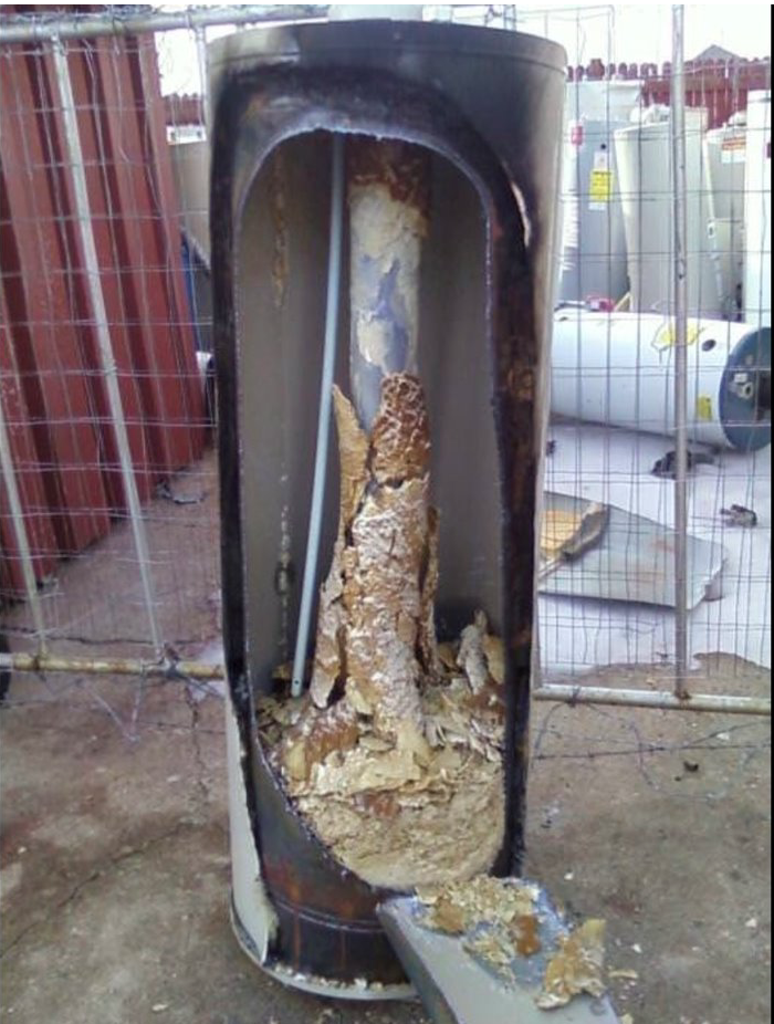 Inside of a corroded water heater showing mineral buildup and damage from untreated water